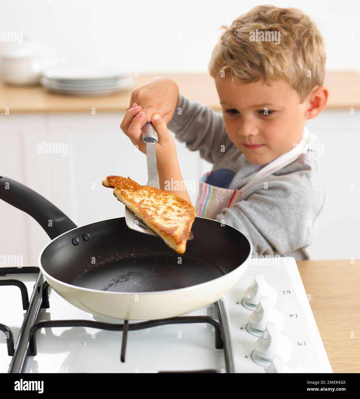 Ein Junge, der Eierbrot in einer Bratpfanne kocht, 4 Jahre Stockfoto