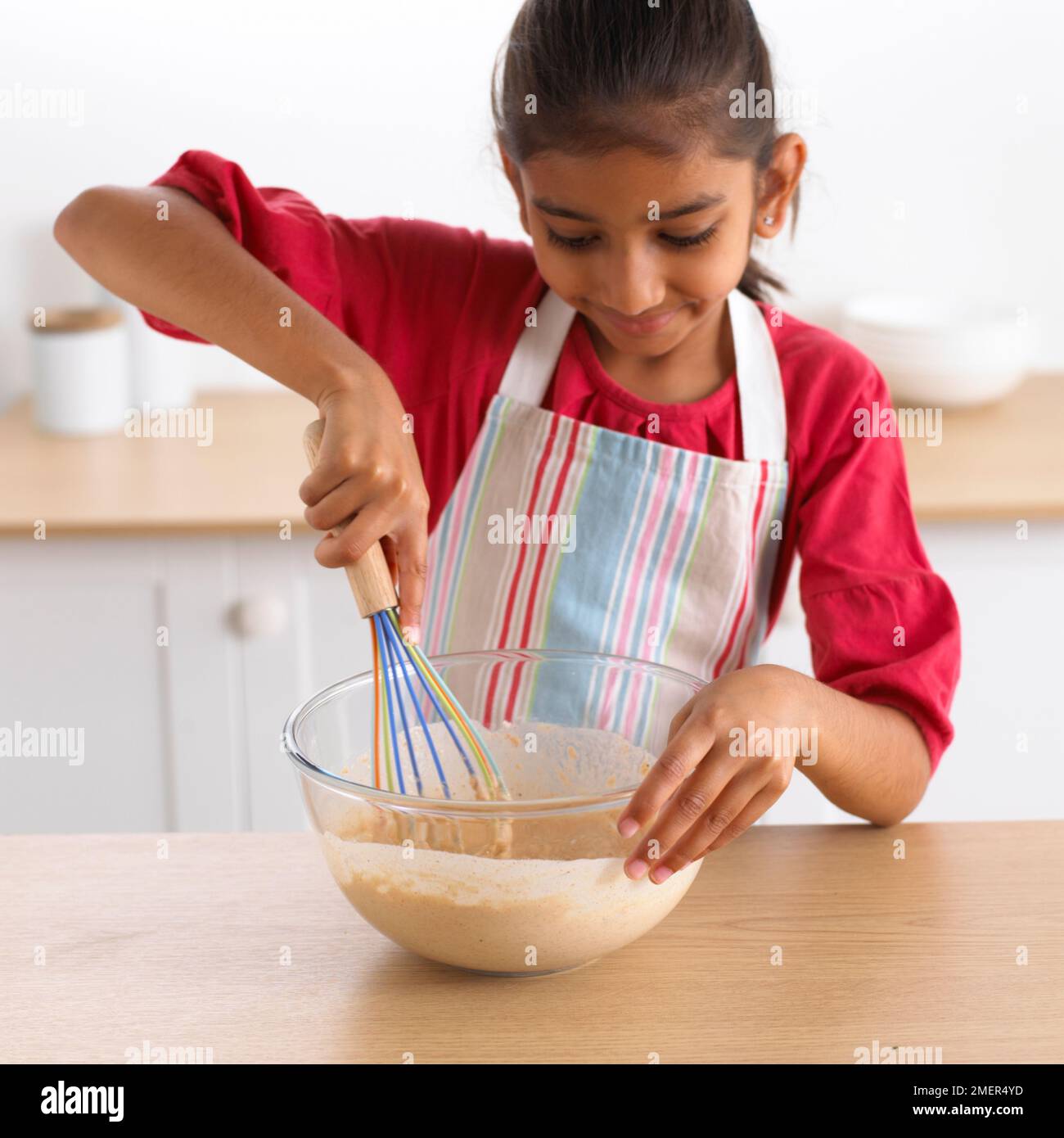 Ein Mädchen, das eine Schüssel Teig rührt, 8 Jahre Stockfoto Ein Mädchen, das eine Schüssel Teig rührt, 8 Jahre Stockfoto