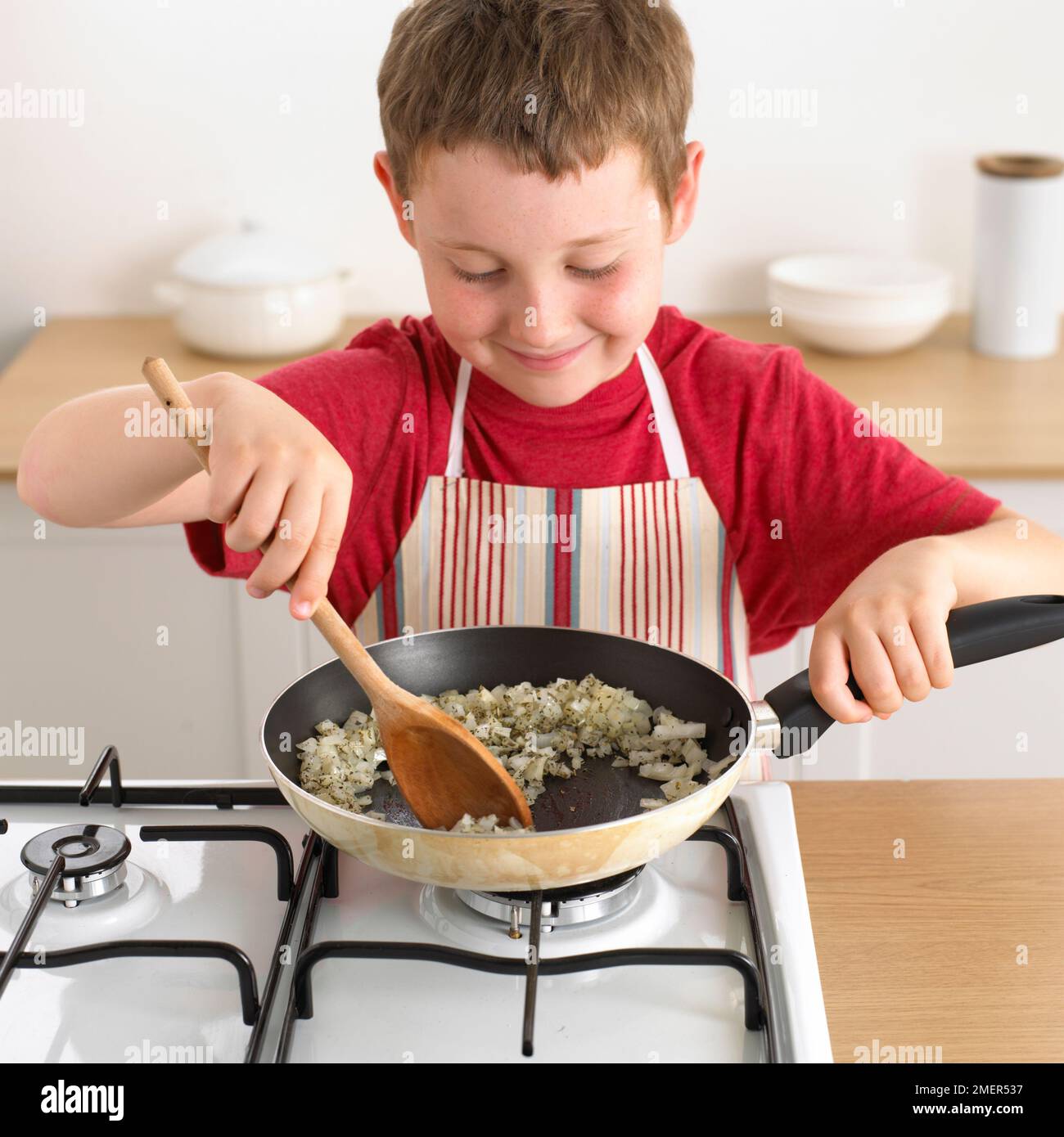 Ein Junge bratte Zwiebeln in der Bratpfanne, 8 Jahre Stockfoto