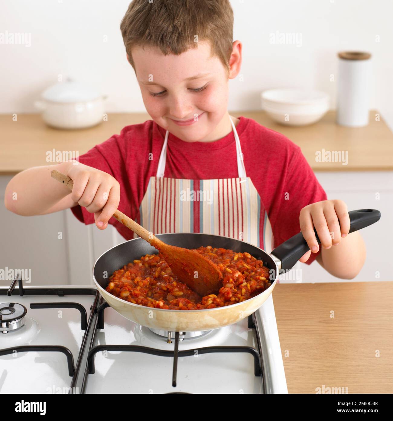 Junge kochen bean Mischung in der Pfanne, 8 Jahre Stockfoto