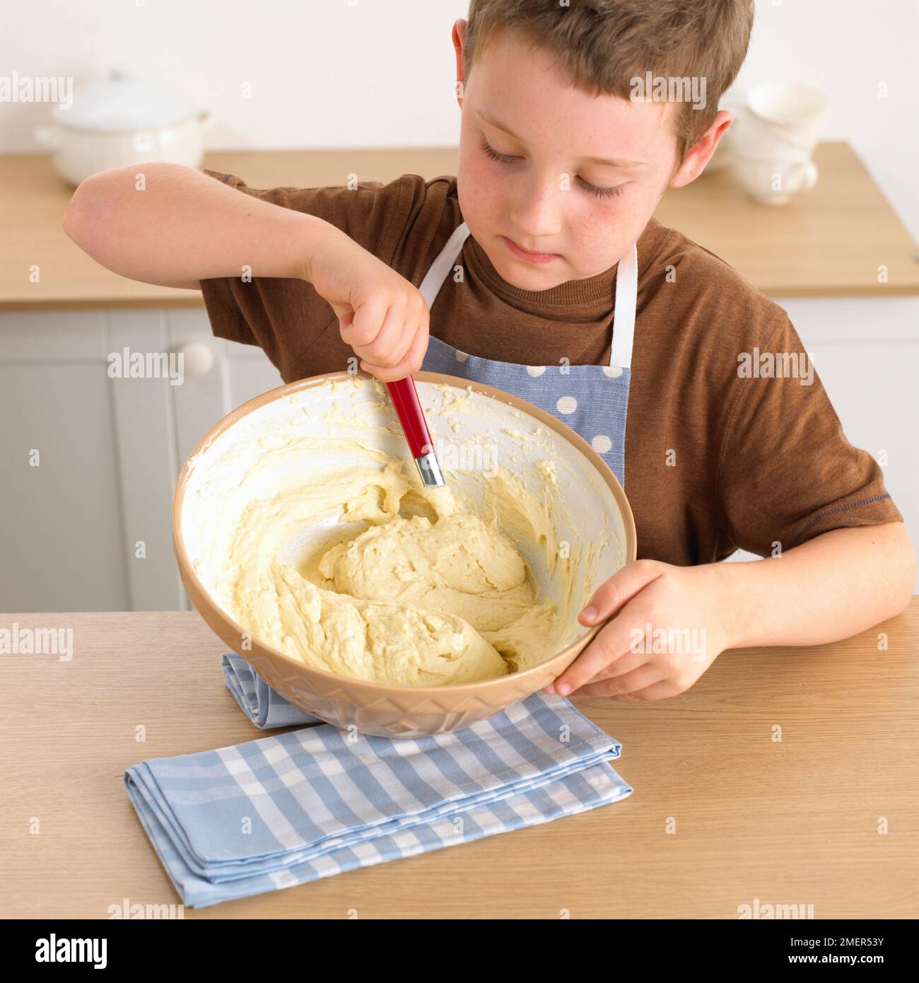 Ein Junge, der eine Schwammmischung in Kuchendosen packt, 8 Jahre Stockfoto