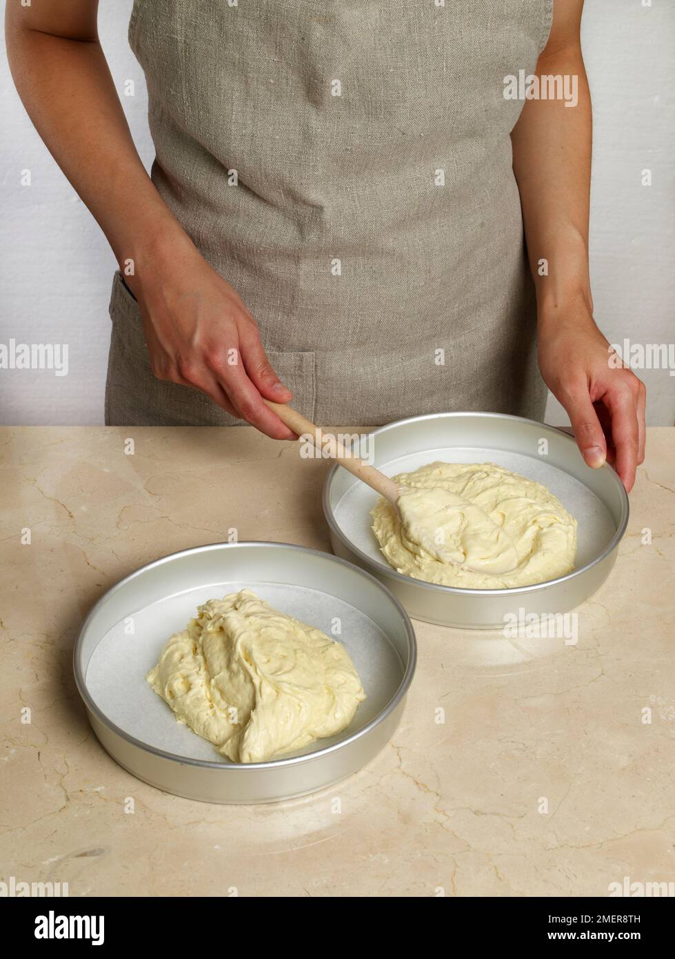 Frau, die glutenfreie Kuchenmischung in zwei Dosen verteilt Stockfoto