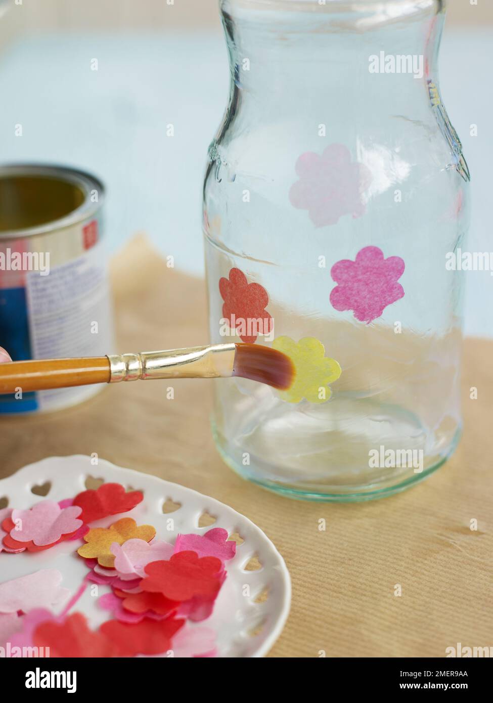 Dekorieren Sie Glasbecher mit Blüten aus Papiertüchern, kleben Sie sie auf eine Schicht Klarlack, und machen Sie Glasbecher aus Kerzenglas Stockfoto