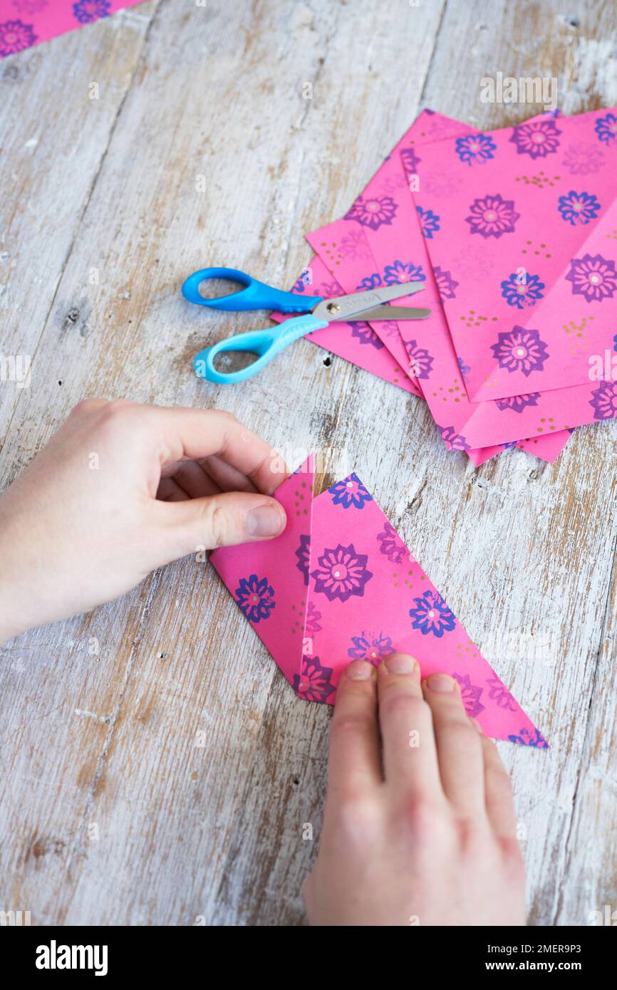 Papierblumen machen, farbenfrohes gemustertes Papier falten Stockfoto