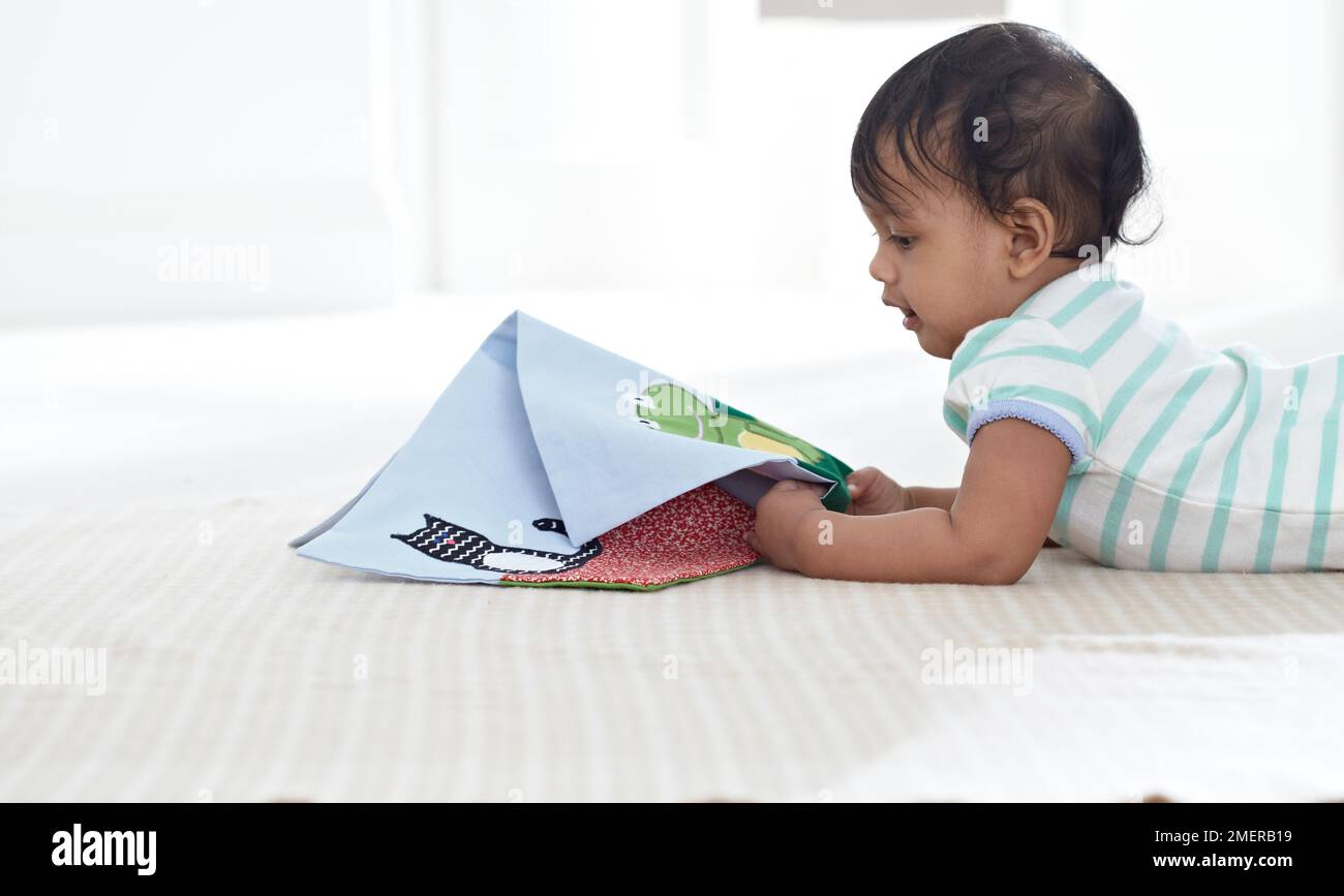 Ein kleines Mädchen, das Stoffbilderbuch liest, 11 Monate Stockfoto