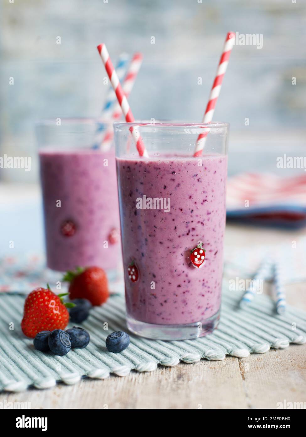 Zwei Gläser mit Strohhalmen, die Erdbeeren- und HeidelbeerSmoothies enthalten Stockfoto
