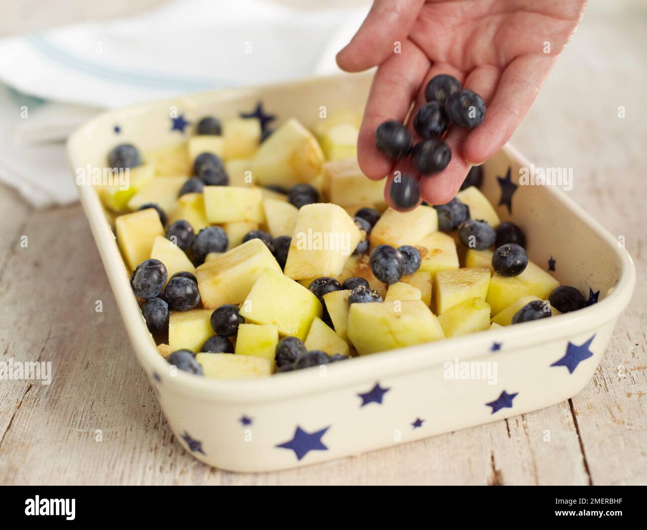 Apfel- und Traubenbröckelkuchen, wobei Trauben in die Tortenform gegeben werden Stockfoto