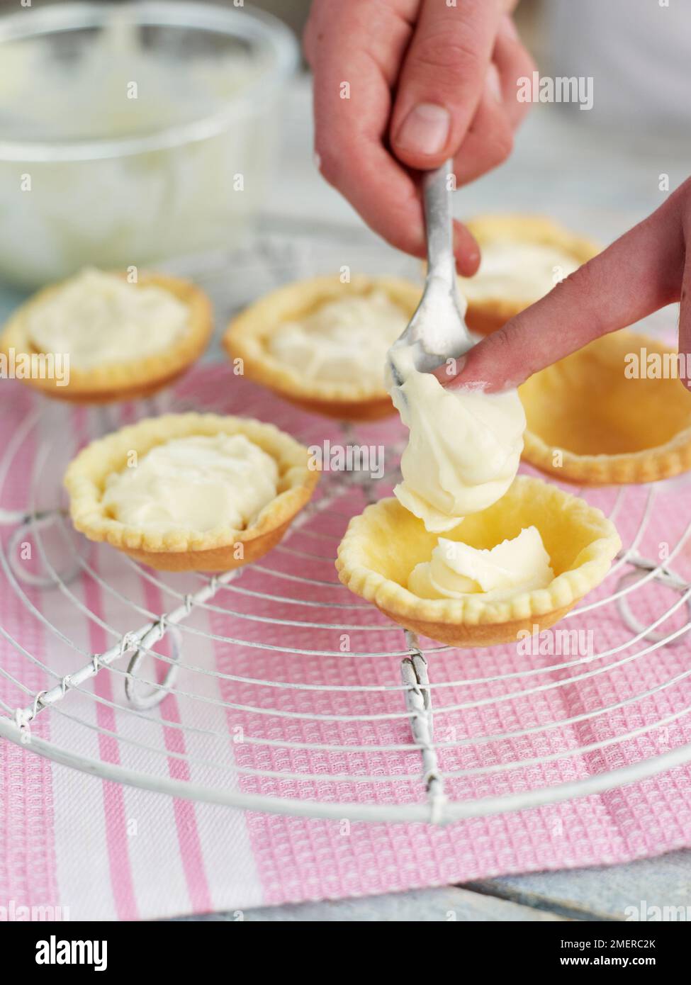 Füllung von Gebäckkisten mit Vanille- und Mascarponmischung, Herstellung von Obsttörtchen Stockfoto