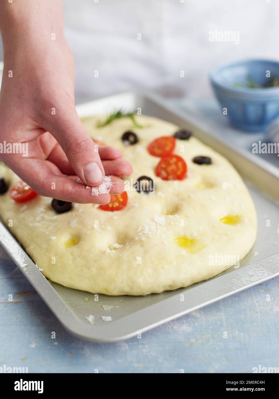 Fokaccia-Brot mit Oliven und Kirschtomaten stopfen und Salz hinzufügen Stockfoto