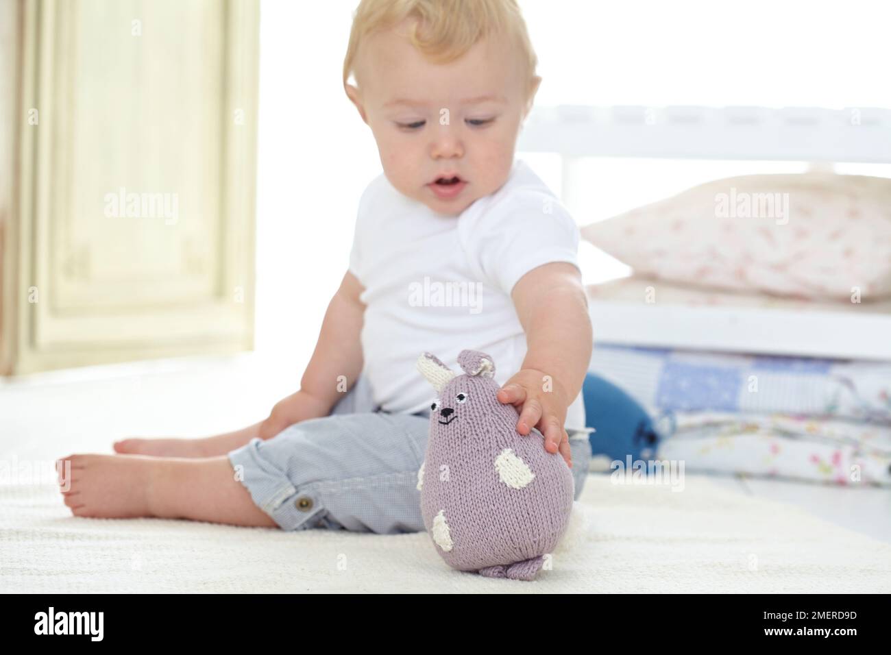 Babyjunge, der mit gestrickten, weichen Tierspielzeugen spielt, 10 Monate Stockfoto