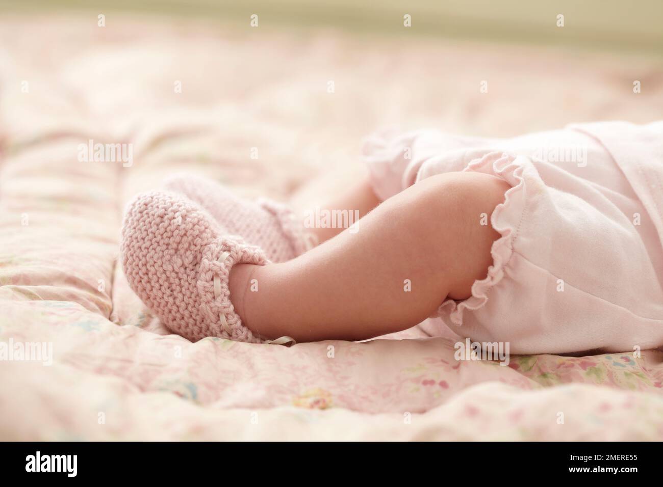 Nahaufnahme von pinkfarbenen Babyschuhen an Babyfüßen, 6 Wochen Stockfoto