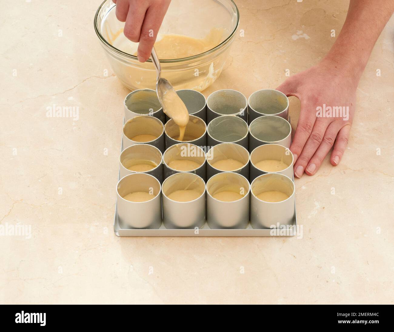 Kleine runde Schimmelpilze mit Kuchenmischung füllen Stockfoto