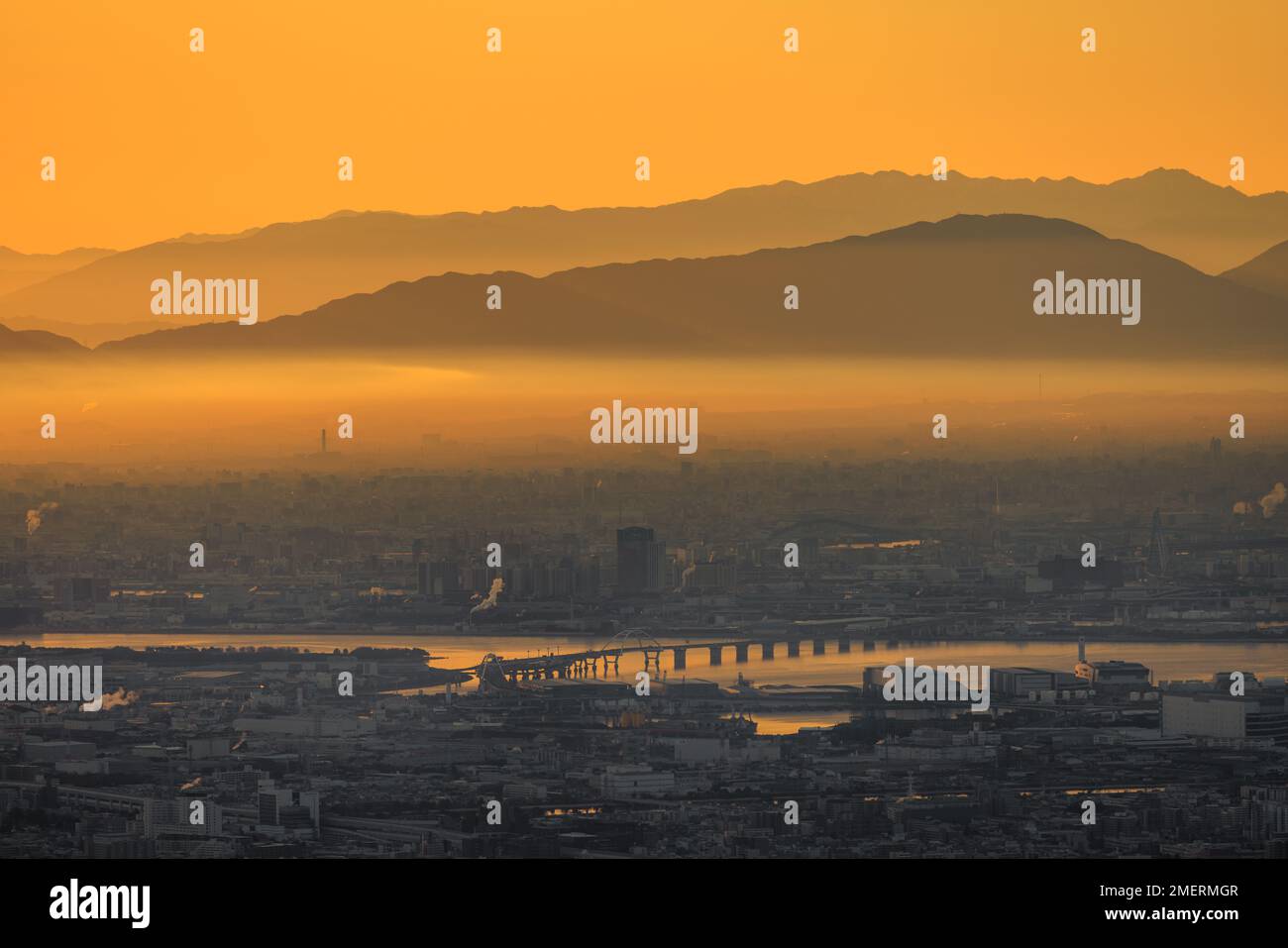 Dicker Smog über Industriestadt mit orangefarbenem Schein am Himmel bei Sonnenaufgang Stockfoto