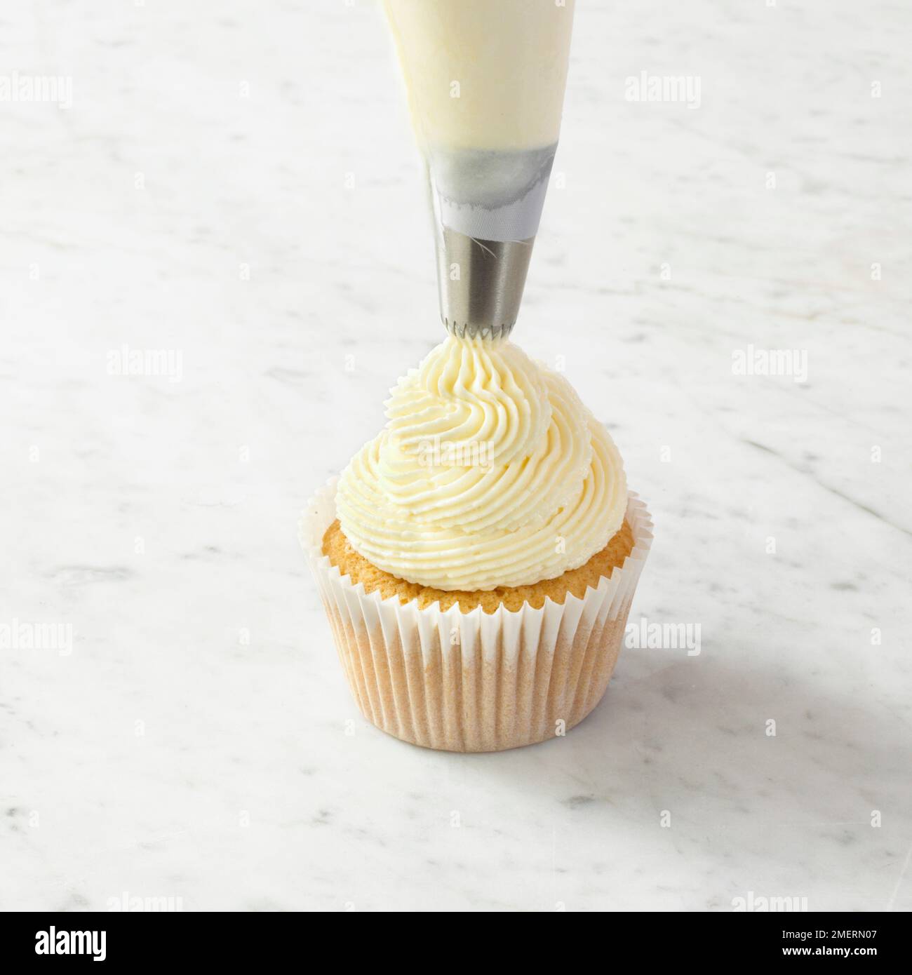Rohrleitungen butter Puderzucker auf Cupcake Stockfoto