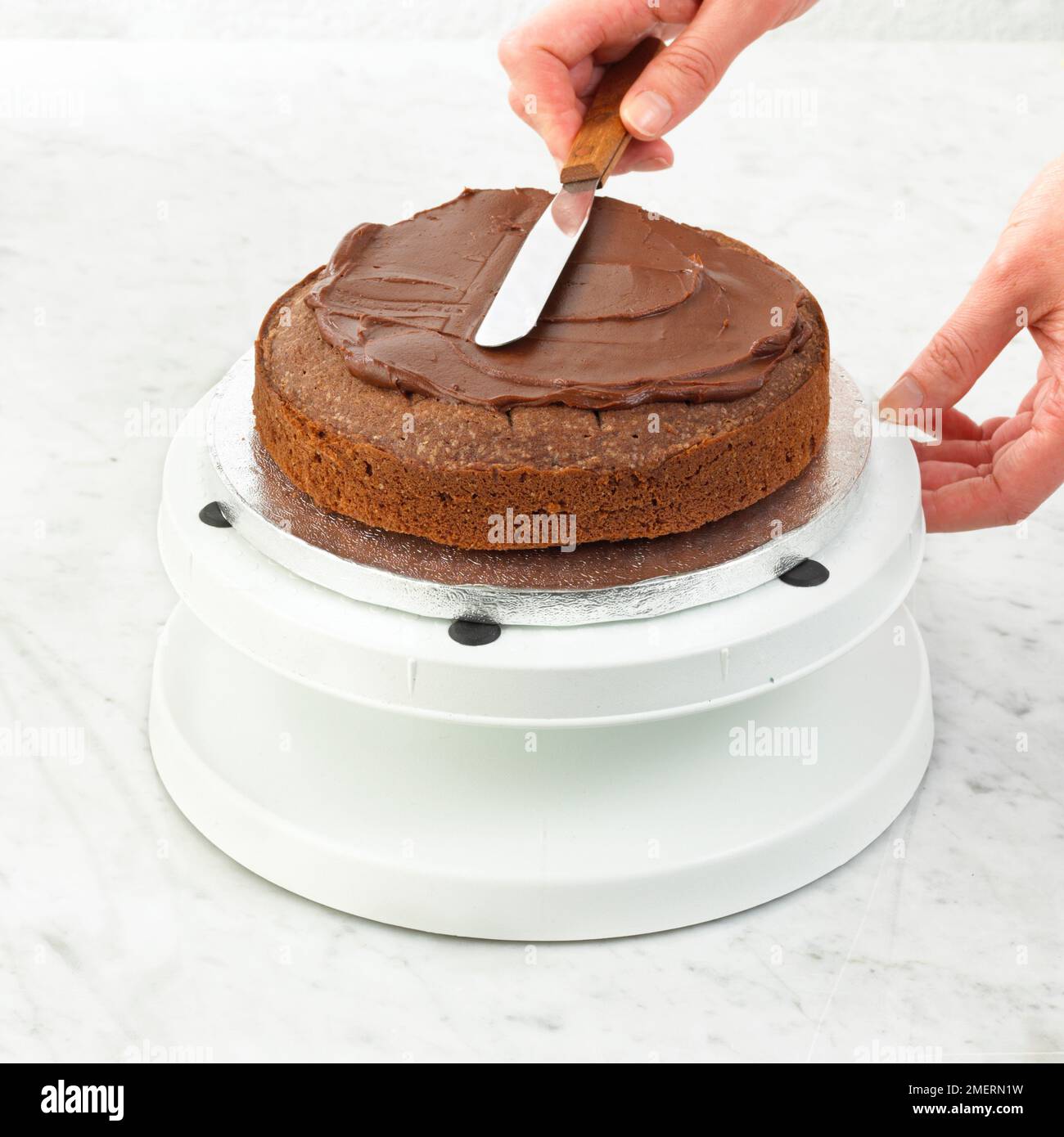 Schokoladenschwammkuchen mit Schokoladenganache-Glasur mit Spachtel Stockfoto
