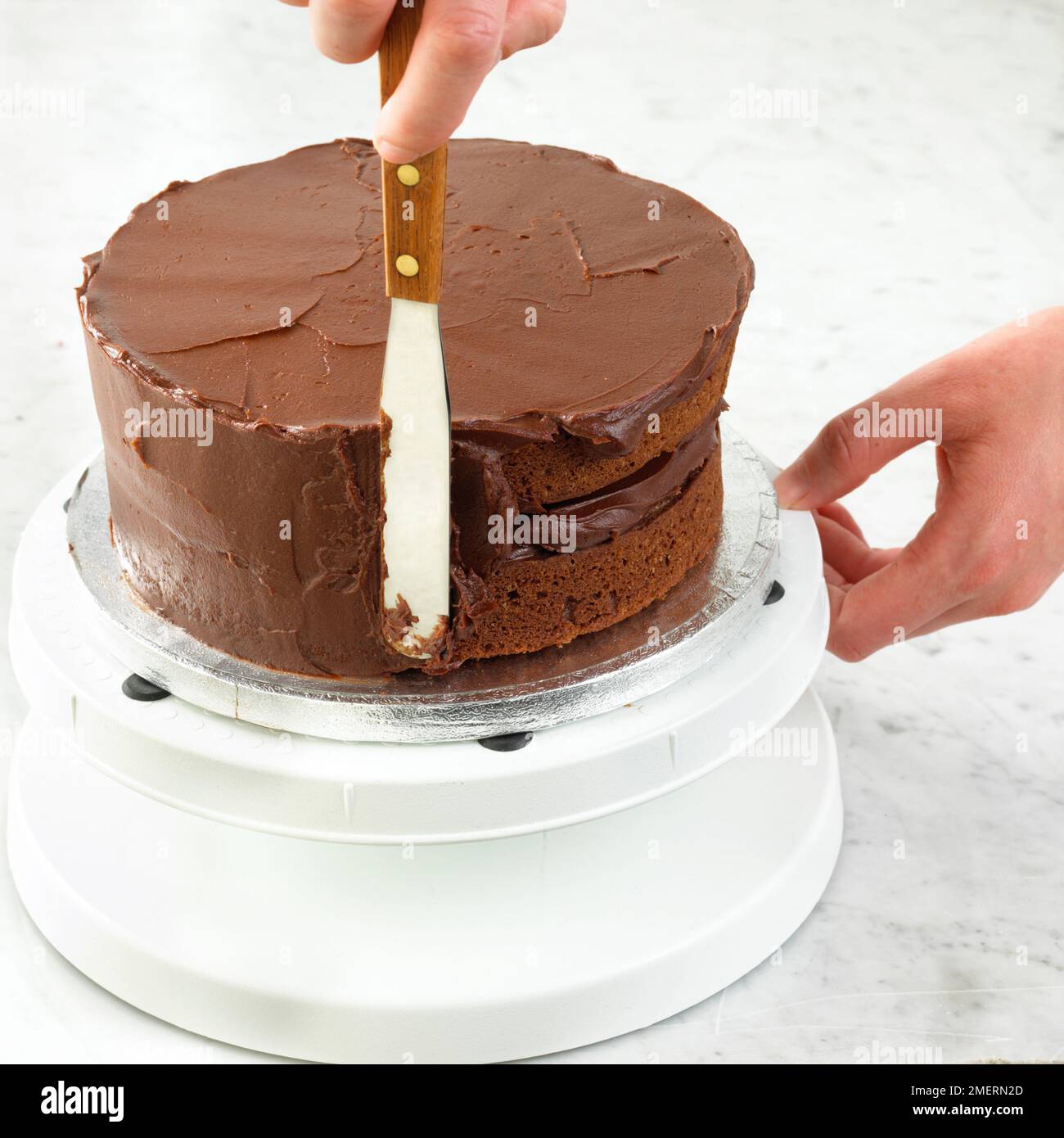 Schokoladenschwammkuchen mit Schokoladenganache-Glasur mit Spachtel Stockfoto