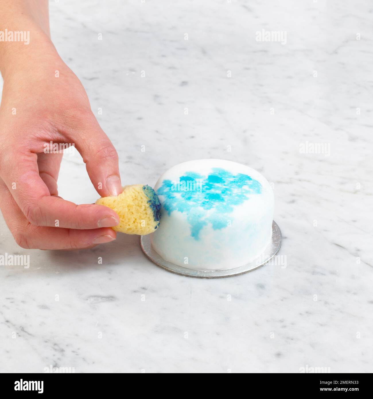 Kuchen bedeckt mit glattem Fondant und mit Schwamm bedruckter blauer Lebensmittelfarbe dekoriert Stockfoto