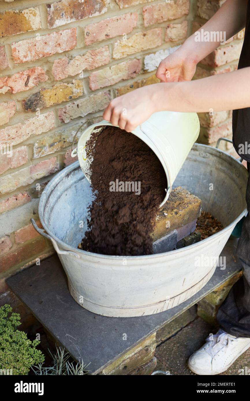 Ein großes, altmodisches Bad aus verzinktem Stahl mit Erde füllen Stockfoto