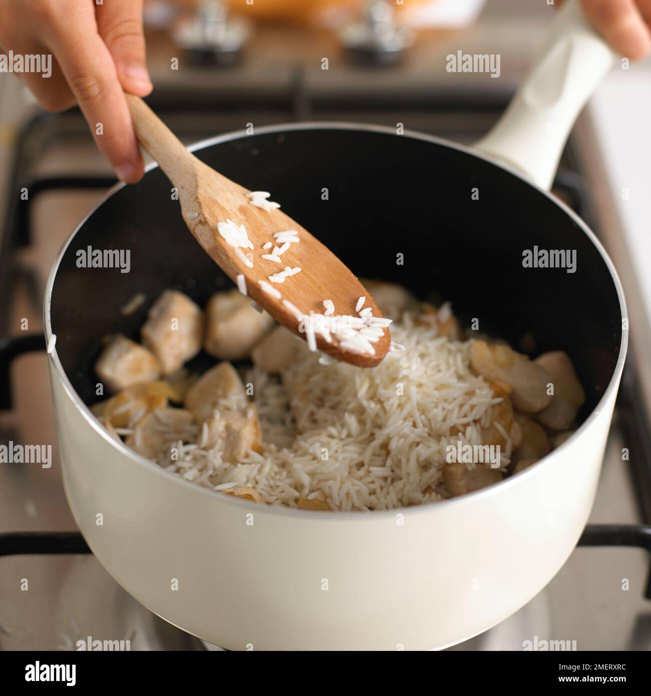 Hähnchen-Risotto machen, Reis und Hähnchen zusammen in einem Topf kochen Stockfoto