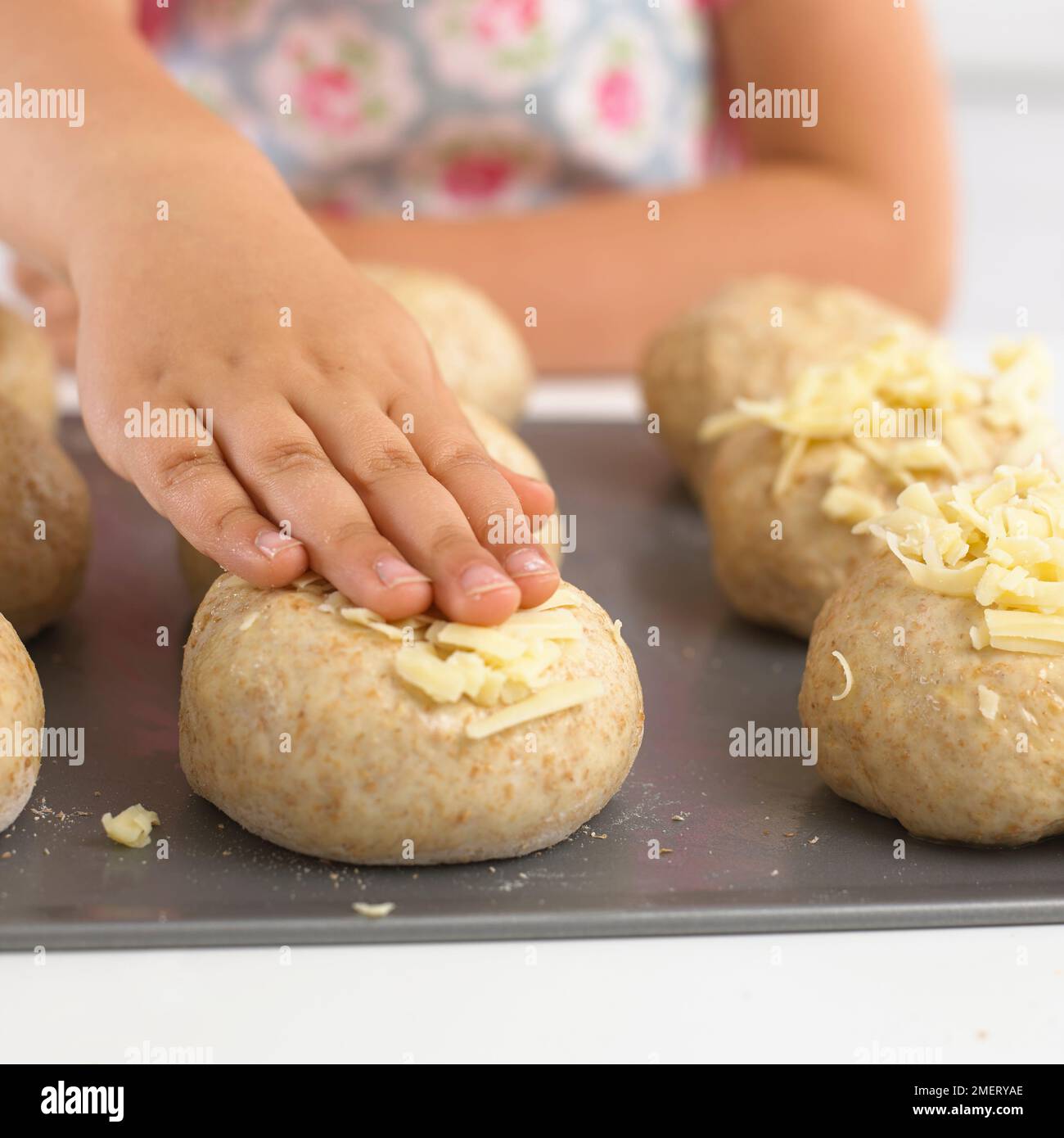 Pressen von geriebenem Käse auf ungekochte Brötchen Stockfoto