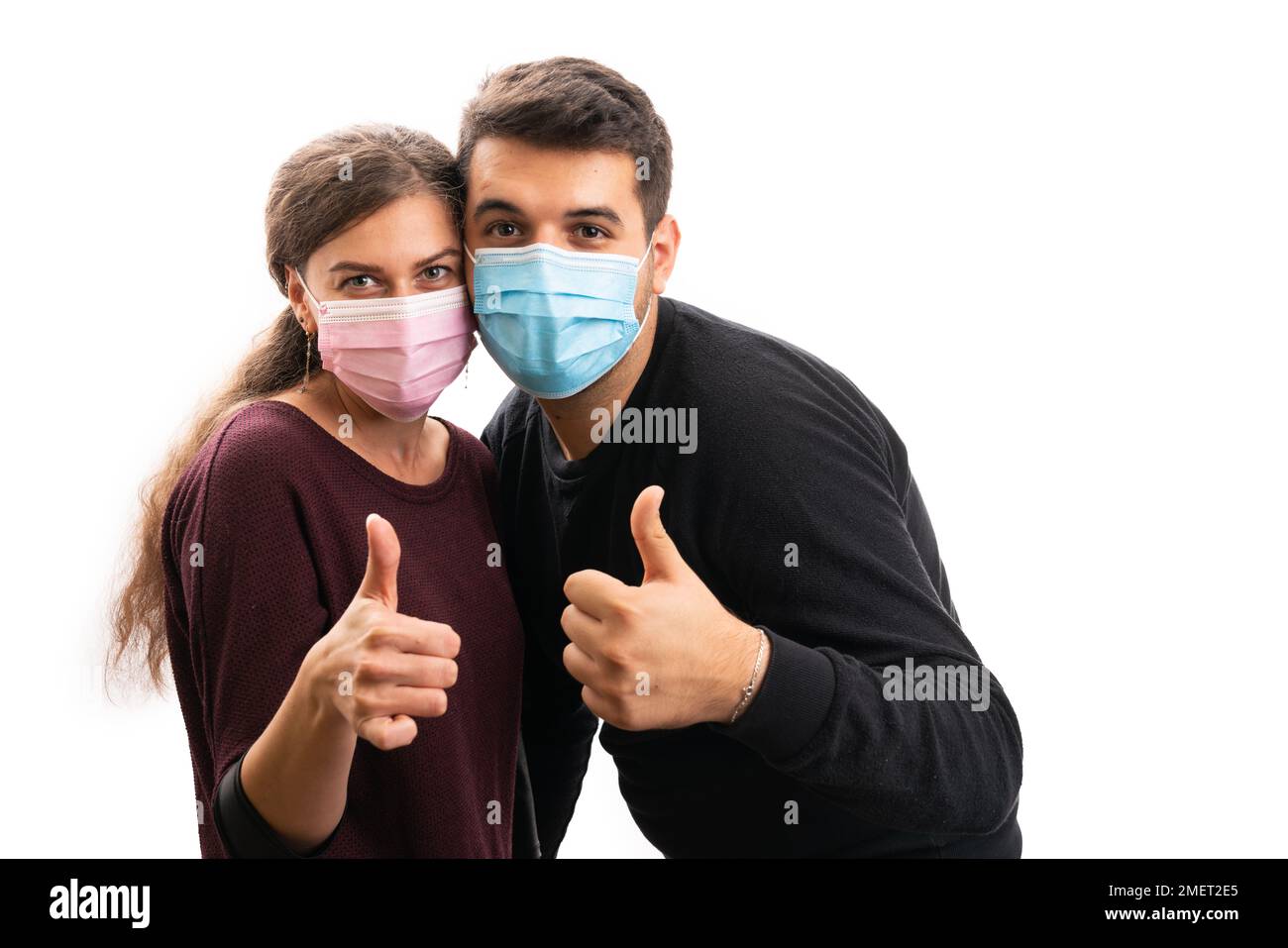 Erwachsene männliche weibliche Ehepaar trägt rosa und blaue medizinische Einweg-Schutzmasken oder chirurgische Schutzmasken machen Daumen-up wie Geste wie sars covid19 Influenza Stockfoto
