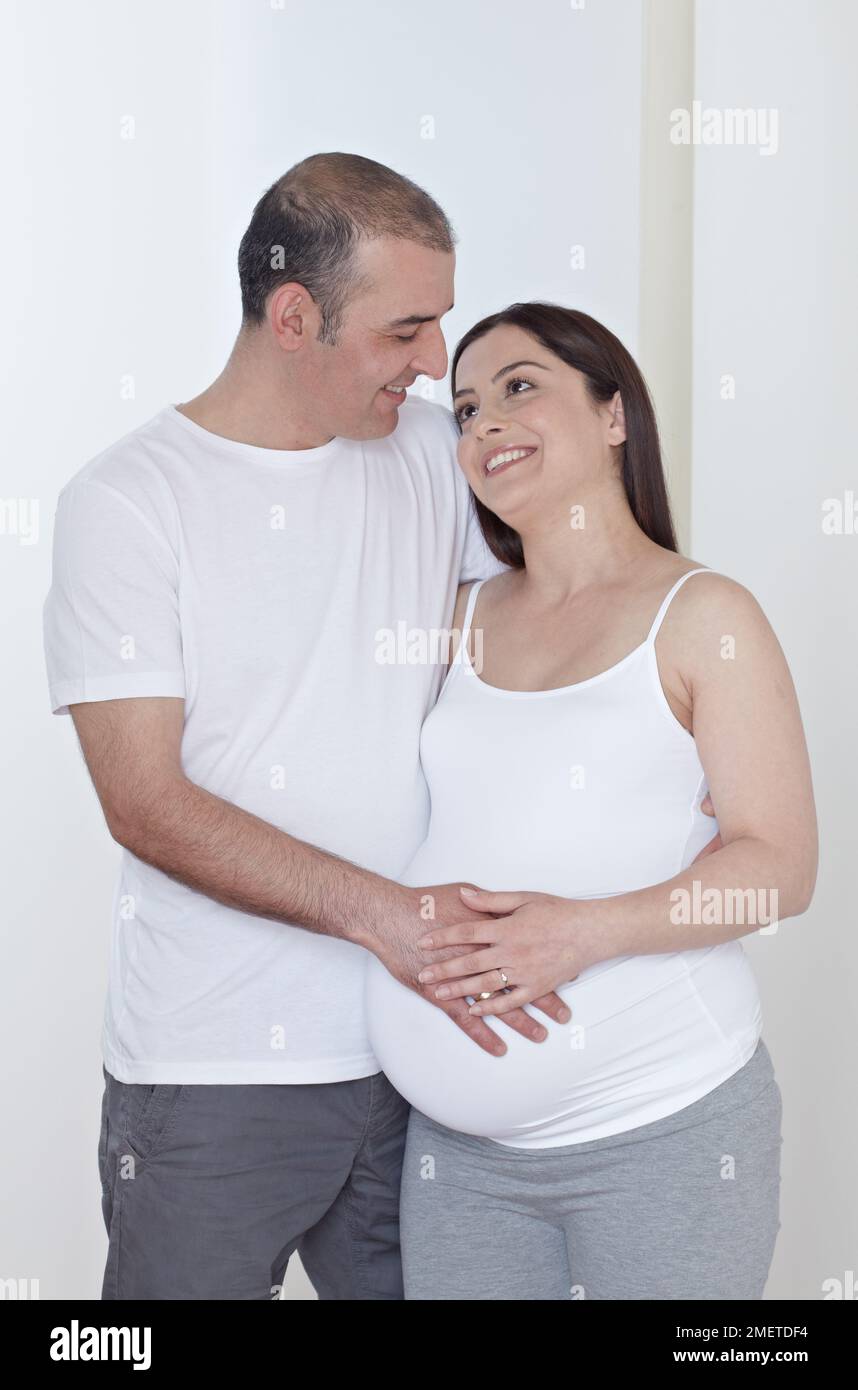 Schwangere Frau mit Partner, Hand berührt ihren Bauch Stockfoto