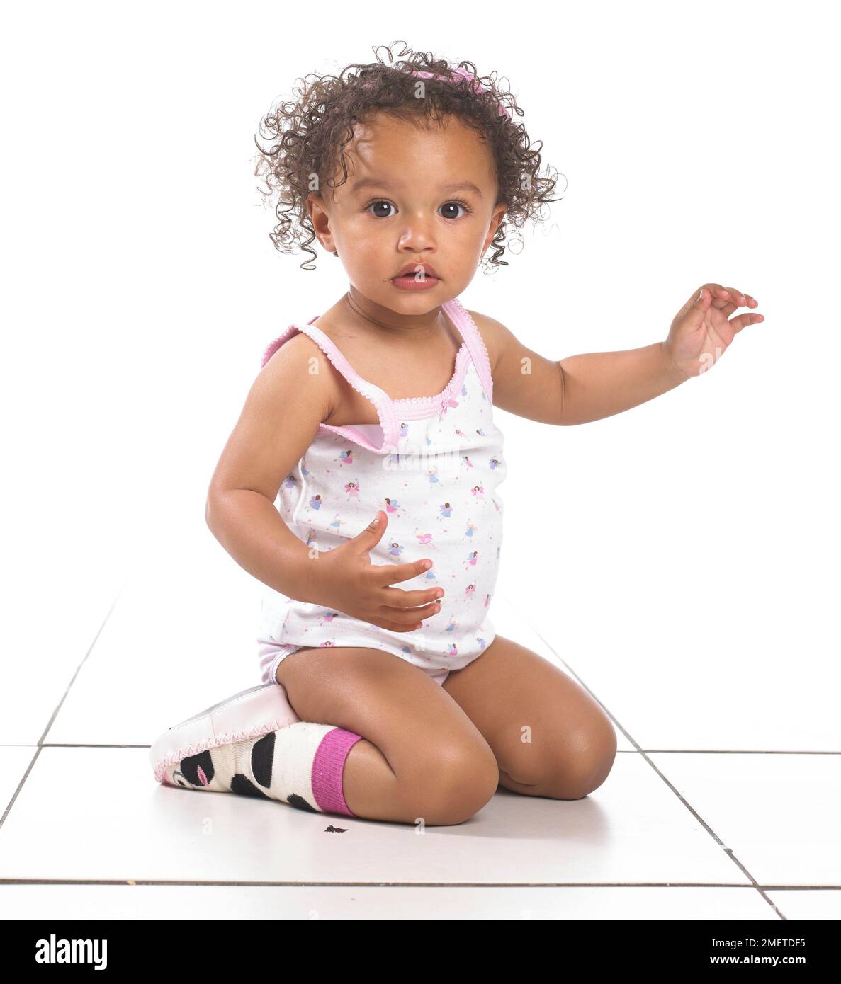 Mädchen mit Weste, Hosen und Hausschuhen, kniend, 16 Monate Stockfoto