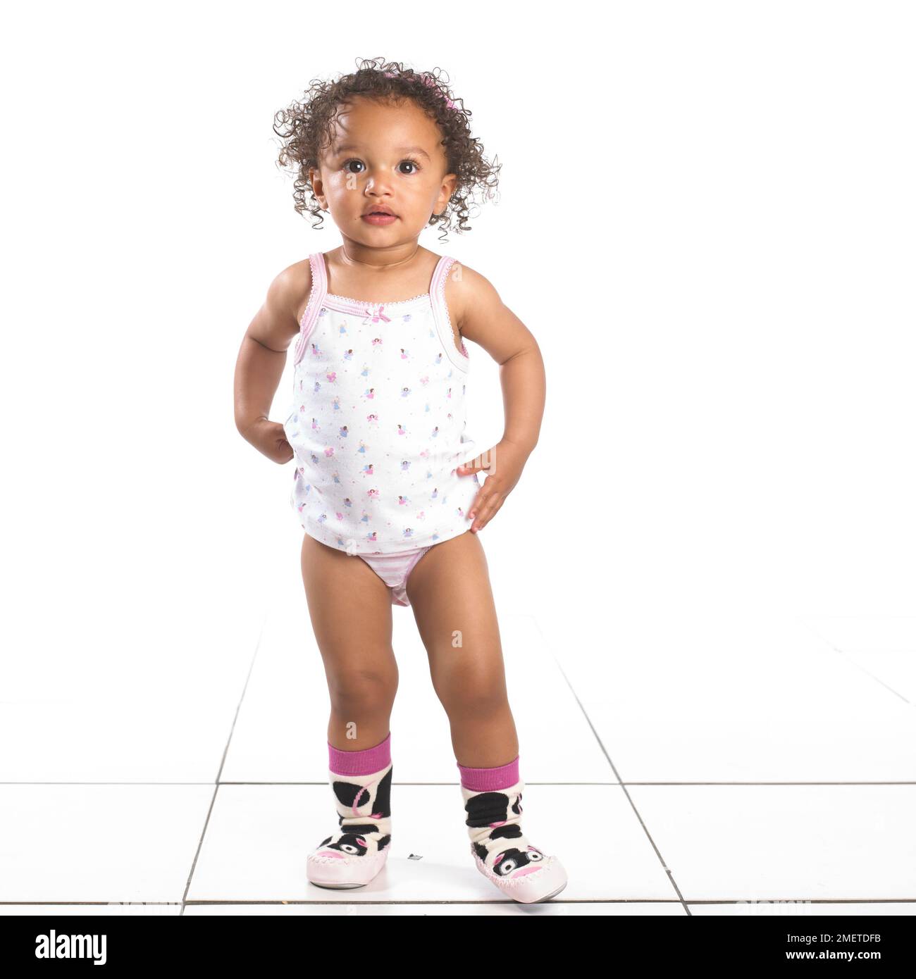 Mädchen mit Hosen, Weste und Hausschuhen im Stehen, 16 Monate Stockfoto