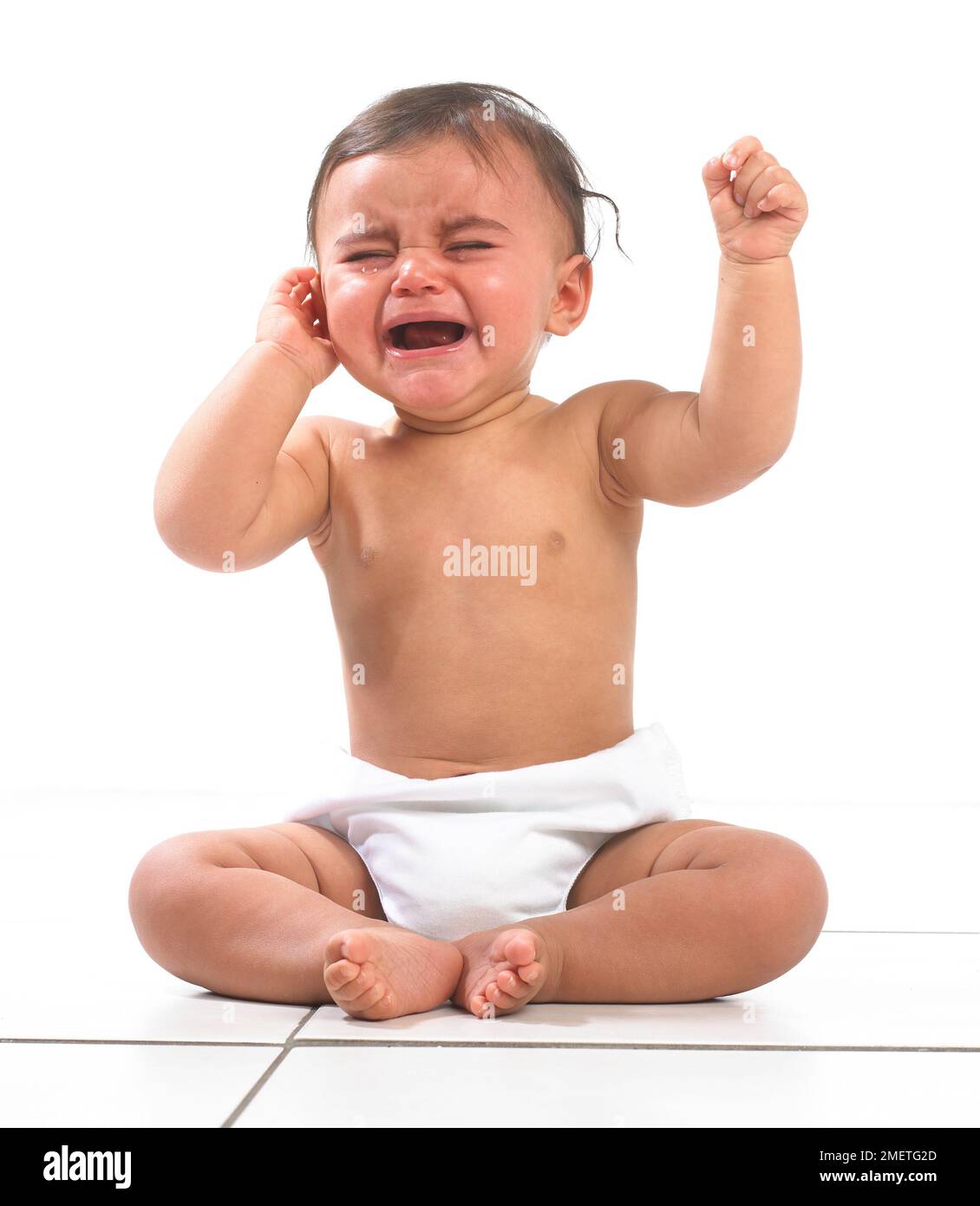 Babymädchen sitzt mit Windel und weint, 7 Monate Stockfoto