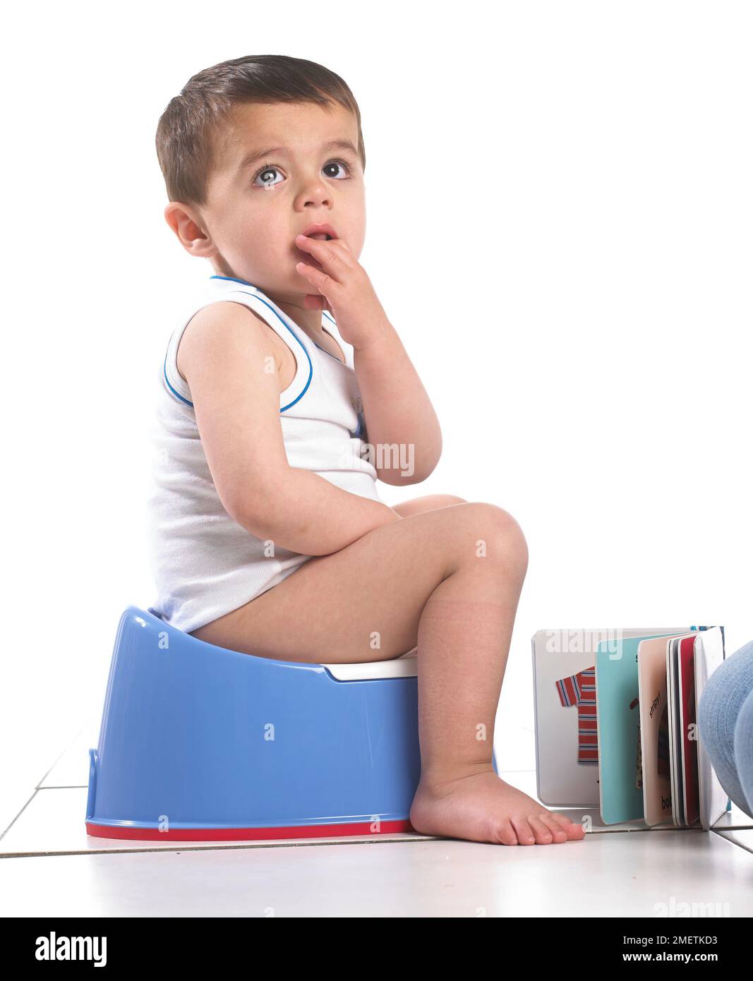 Ein Junge, der eine Weste trägt und auf einem blauen Töpfchen sitzt, 20 Monate Stockfoto