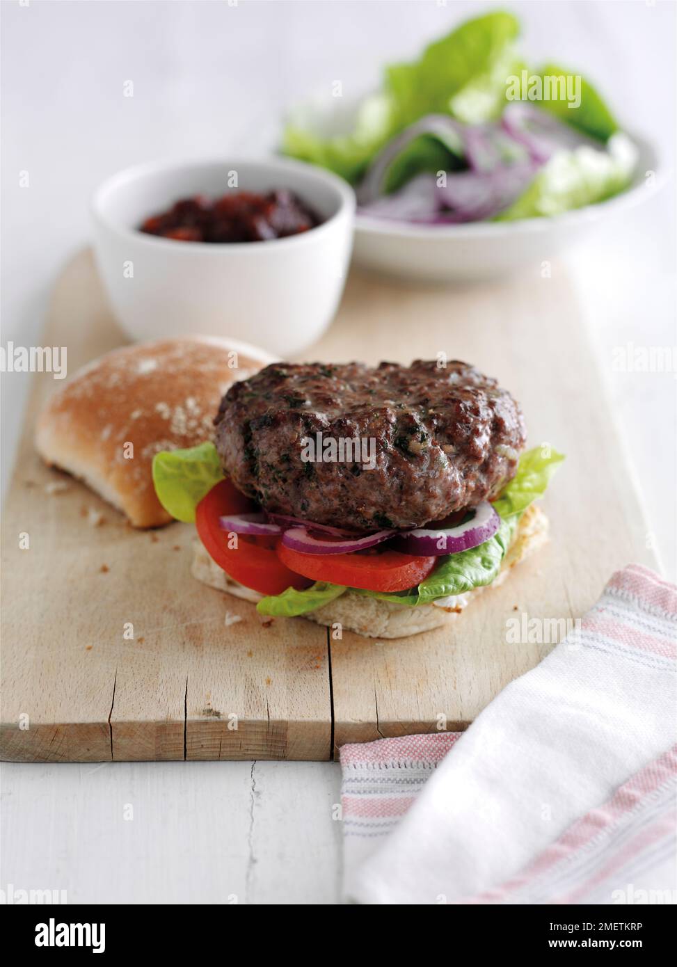 Hausgemachter Rinderburger mit Salat, Tomaten, roten Zwiebeln, in Brötchen Stockfoto