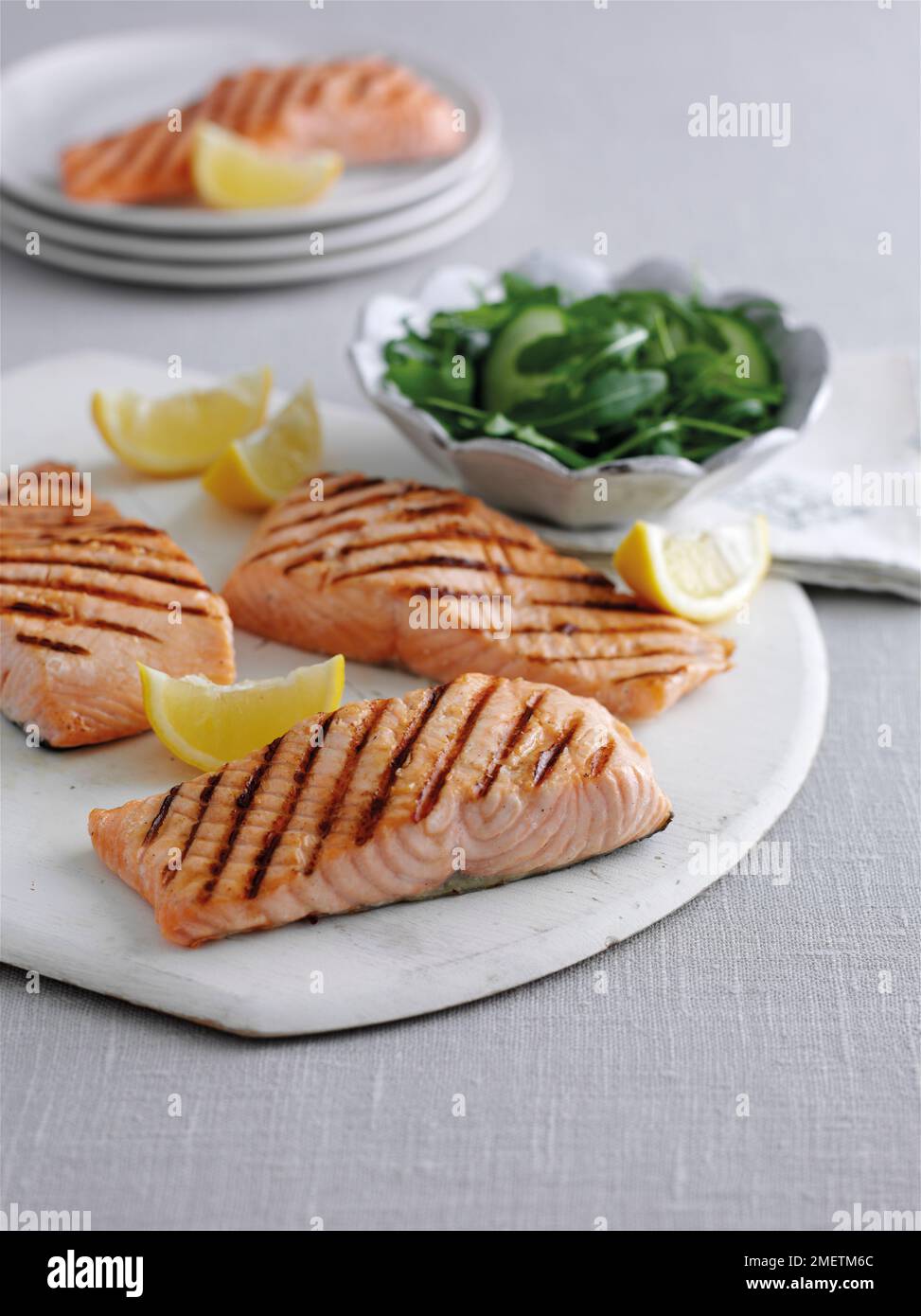 Gegrillte Lachsfilets mit Zitronenspalten und Beilagensalat Stockfoto