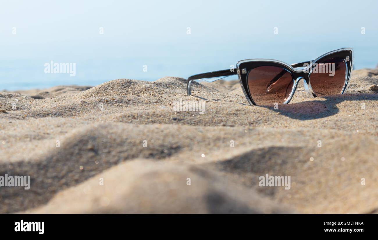 Sonnenbrille am Strand. Entspannungsurlaub - Blaues Meer, weißer Sand, strahlende Sonne am Strand. Stockfoto