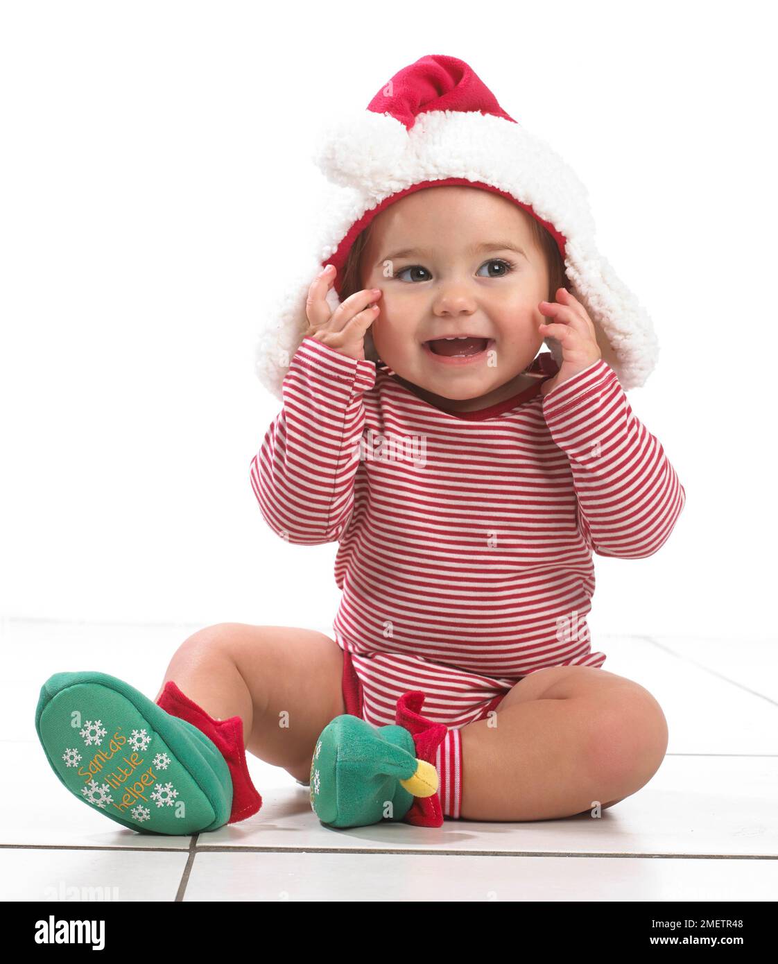 Kleines Mädchen (12 Monate) mit weihnachtsmütze und Elfenschühchen Stockfoto