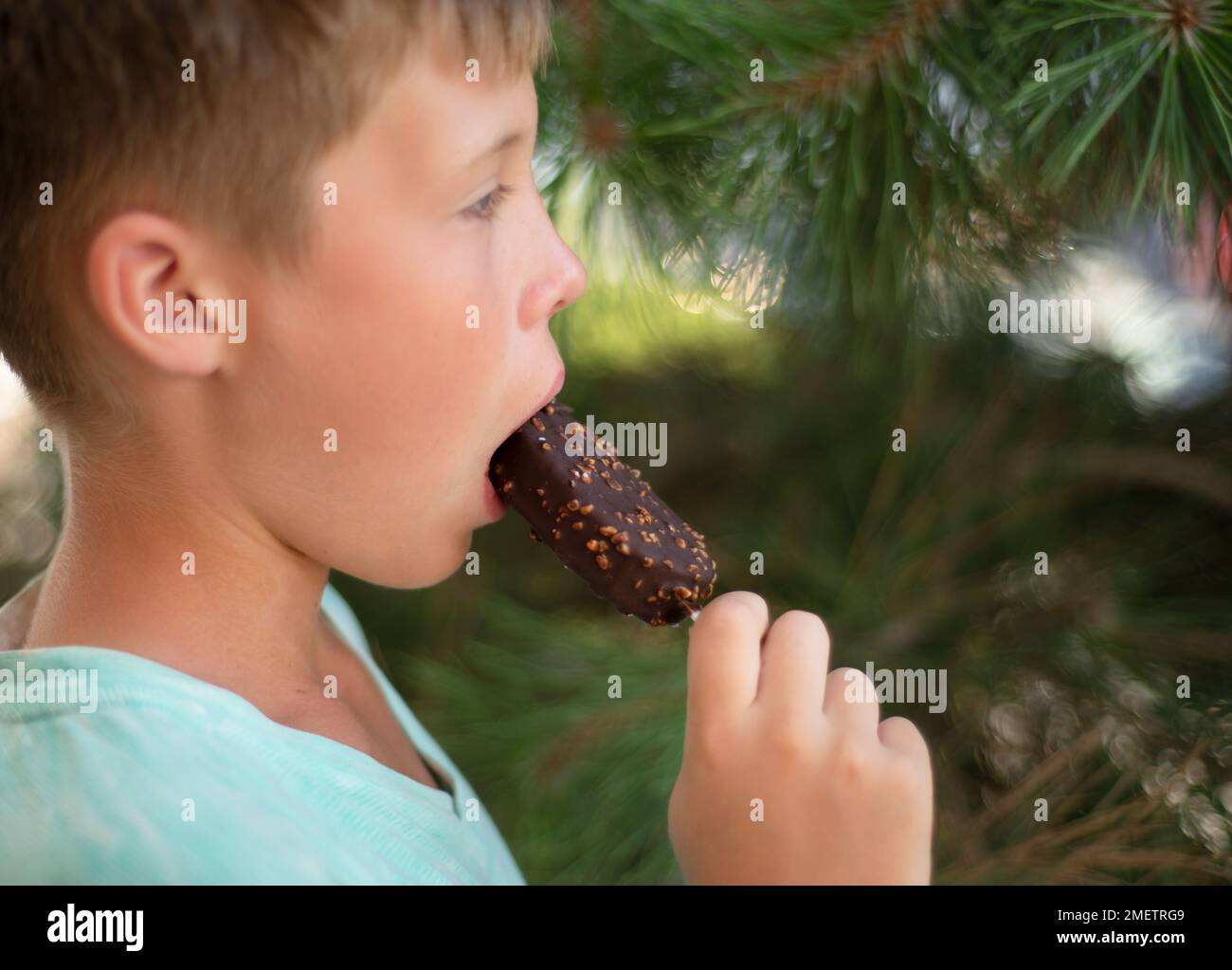 Der Junge isst Eiscreme auf einem Stock in Schokolade. Stockfoto