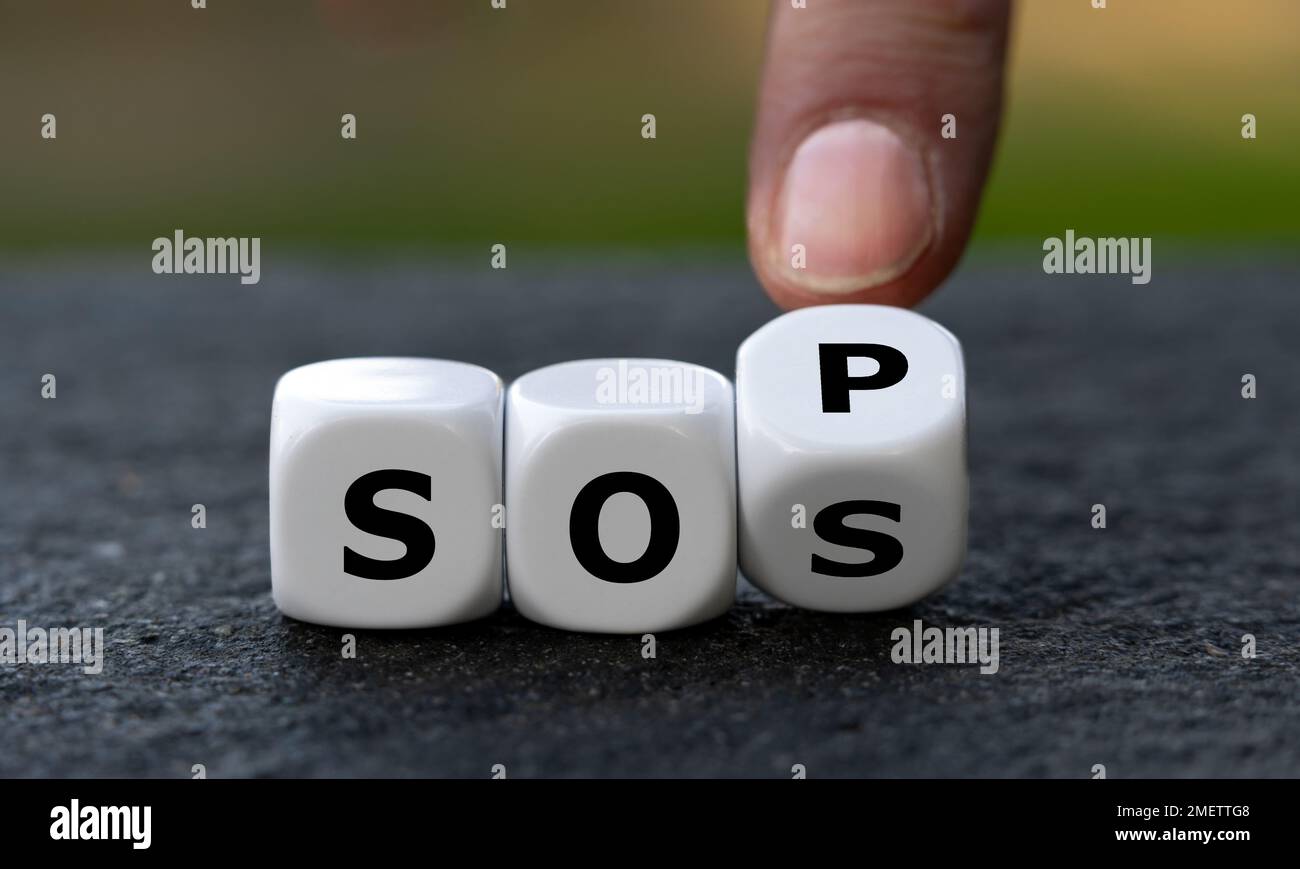 Die Hand dreht Würfel und ändert die Abkürzung SOS (Save our Souls) in SOP (Standard Operating procedure). Symbol für das Abrufen von Hilfe. Stockfoto