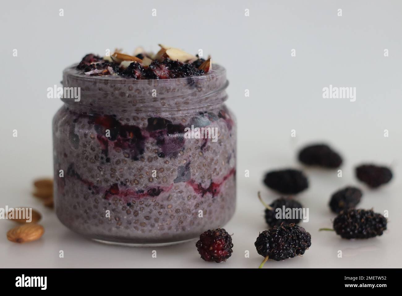 Oats Chia Pudding über Nacht serviert mit Maulbeeren und gehackten Mandeln. Ein gesundes Frühstück ohne Kochen. Aufnahme auf weißem Hintergrund entlang w Stockfoto
