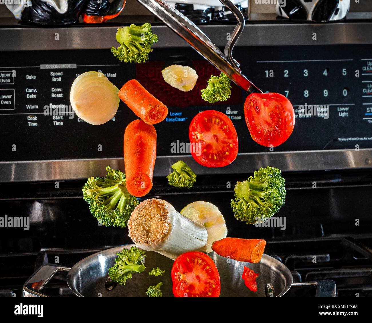 Explodierend.fliegendes Gemüse über einem Topf in der Küche.gesunde Gemüsesuppe voller Vitamine.Lasst uns gesund essen! Stockfoto Explodierend.fliegendes Gemüse über einem Topf in der Küche.gesunde Gemüsesuppe voller Vitamine.Lasst uns gesund essen! Stockfoto