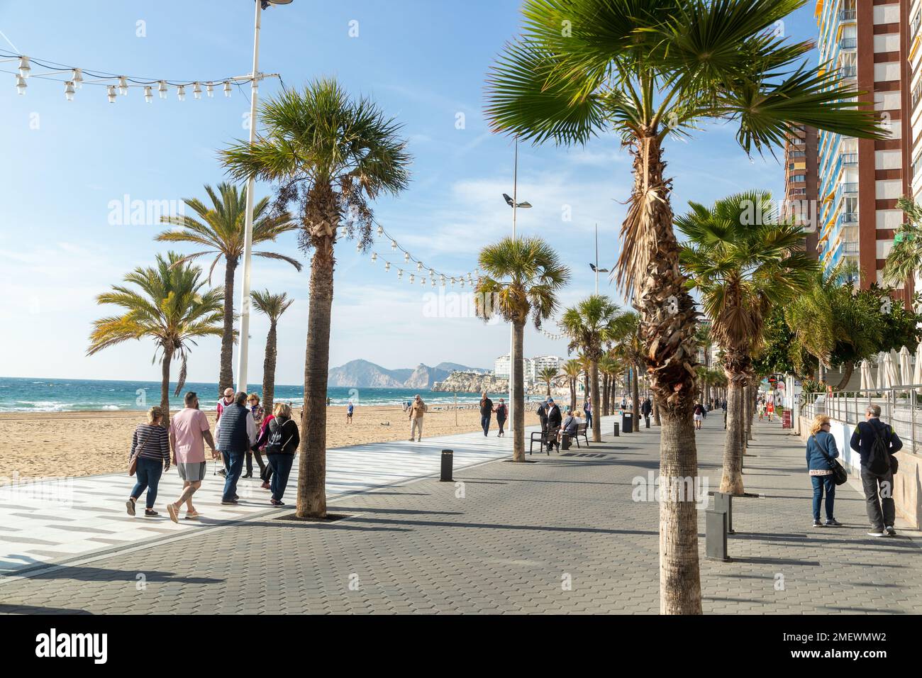 Leute genießen einen Spaziergang entlang der Promenade an der Küste von Benidorm Stockfoto