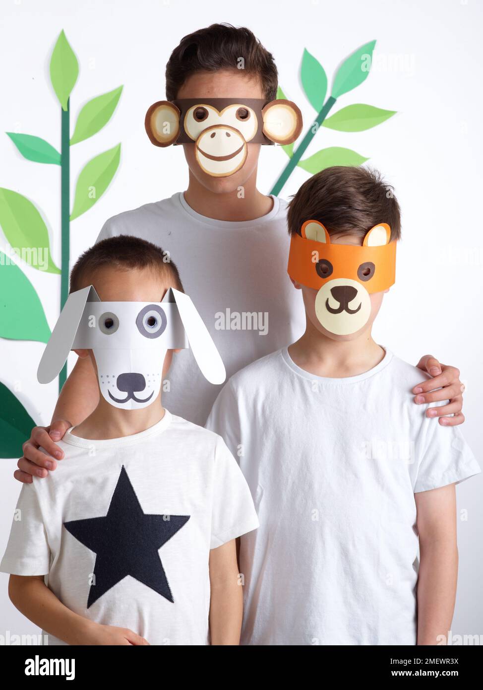 Papierhandwerk. Heimwerker-Tiermasken. Kinder in weißen T-Shirts mit Tiermasken. Affe, Bär und Hund. Stockfoto