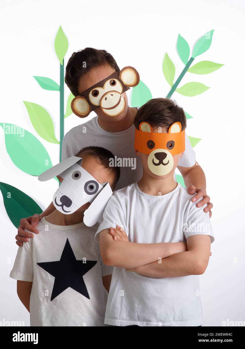 Papierhandwerk. Heimwerker-Tiermasken. Kinder in weißen T-Shirts mit Tiermasken. Affe, Bär und Hund. Stockfoto