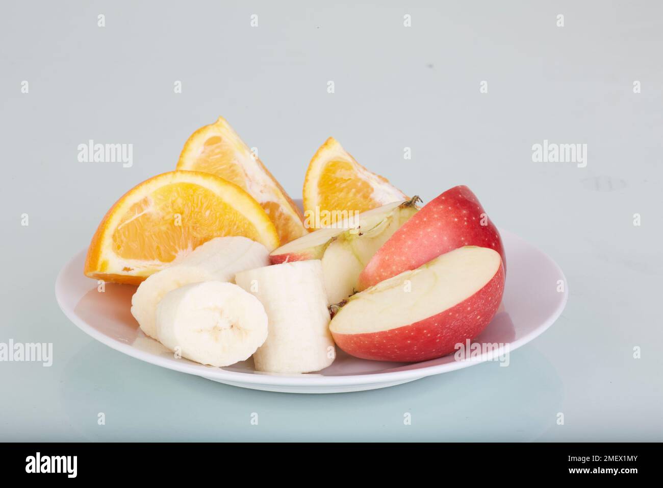 Orangen-, Apfel- und Bananenscheiben auf einem Teller Stockfoto