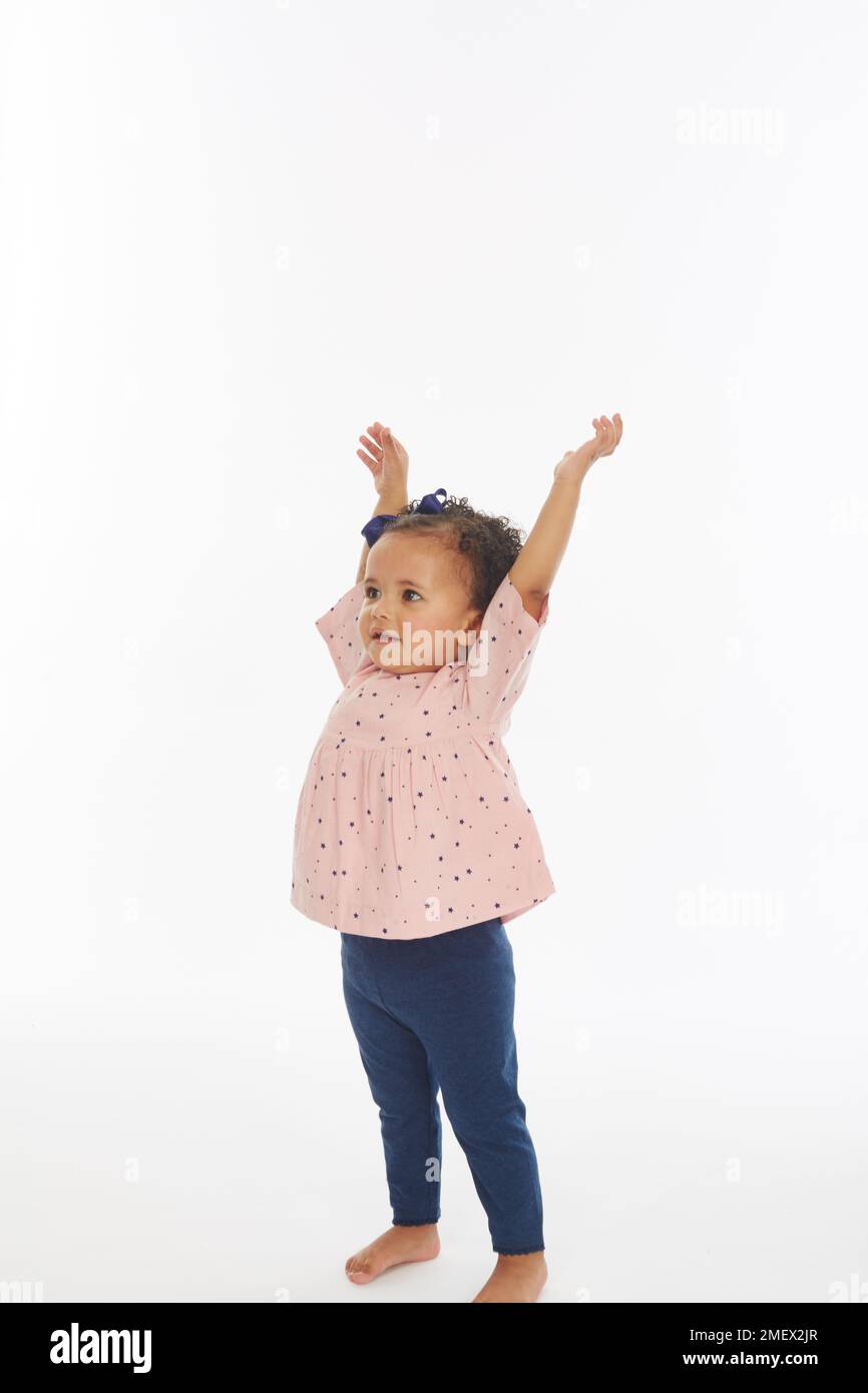 Kleines Mädchen in pinkfarbenem Oberteil spielt, verschiedene Posen (Modellalter – 19 Monate) Stockfoto