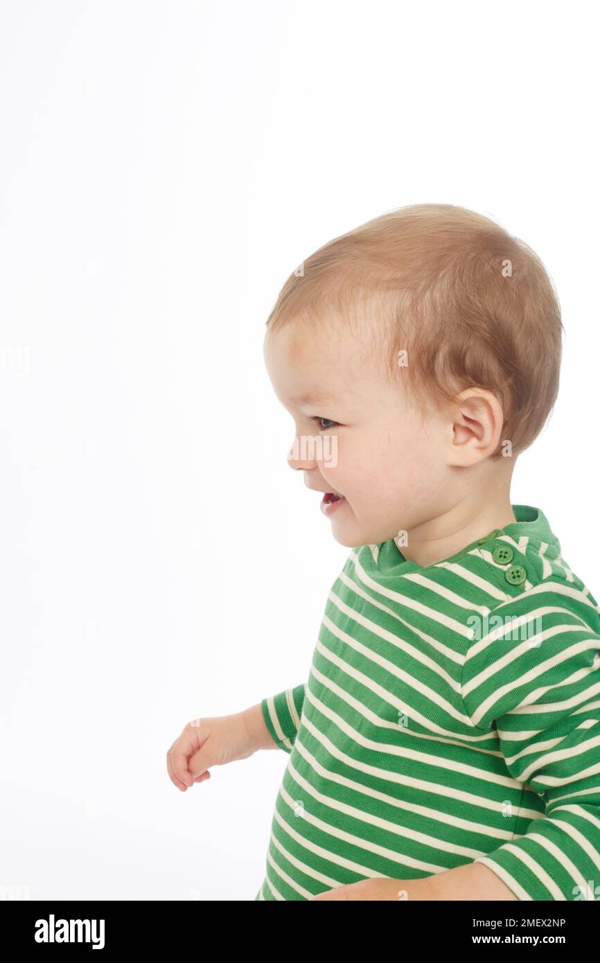 Kleiner Junge in grün gestreiftem Oberteil, lächelnd (Model Age – 22 Monate) Stockfoto