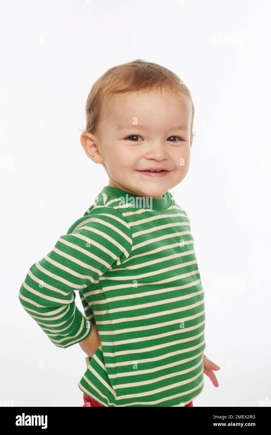 Kleiner Junge in grün gestreiftem Oberteil, lächelnd (Model Age – 22 Monate) Stockfoto