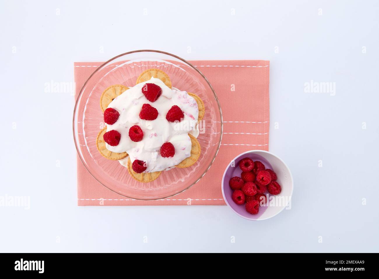 Himbeertorte – Schritt 2: Legen Sie abwechselnd Jammy Biscuits, Creme und Himbeeren auf dem Kuchenständer auf Stockfoto