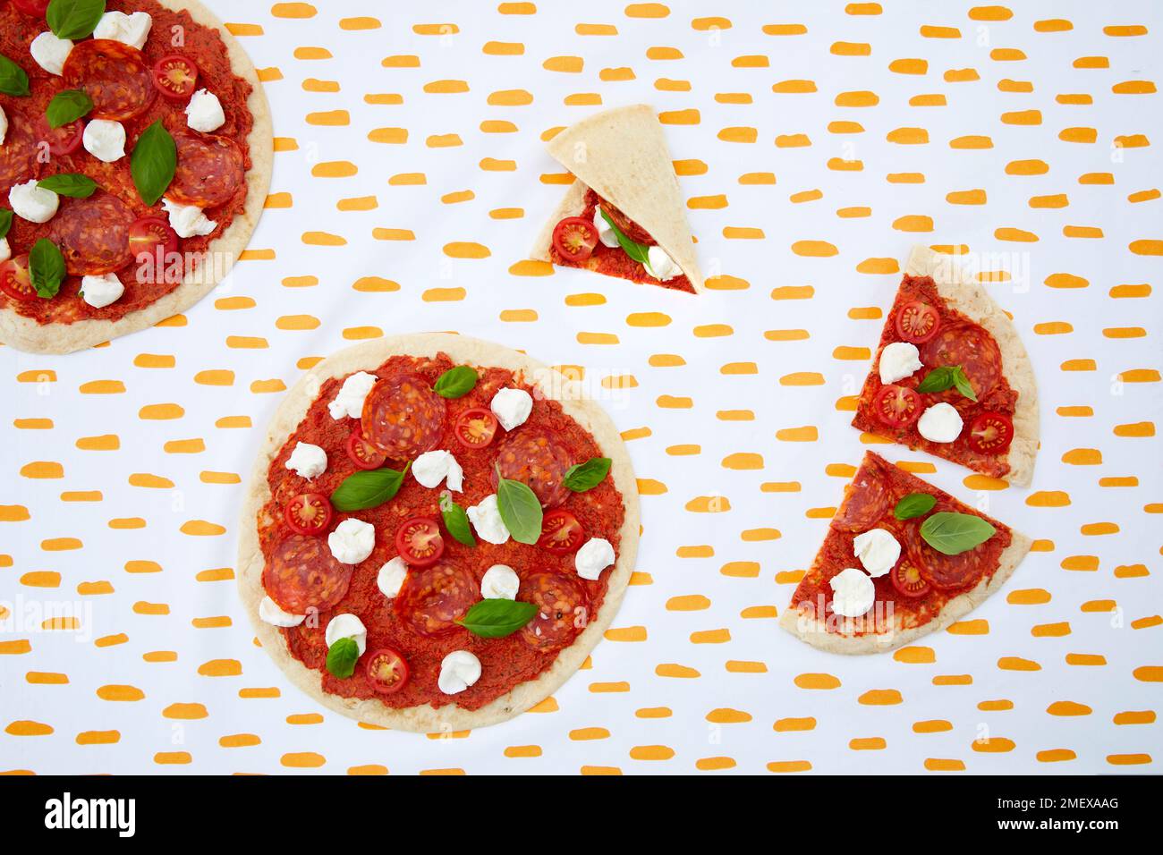 Rohe Pizza mit Tomaten, Mozzarella und Peperoni über dem Kopf auf gemustertem Hintergrund Stockfoto