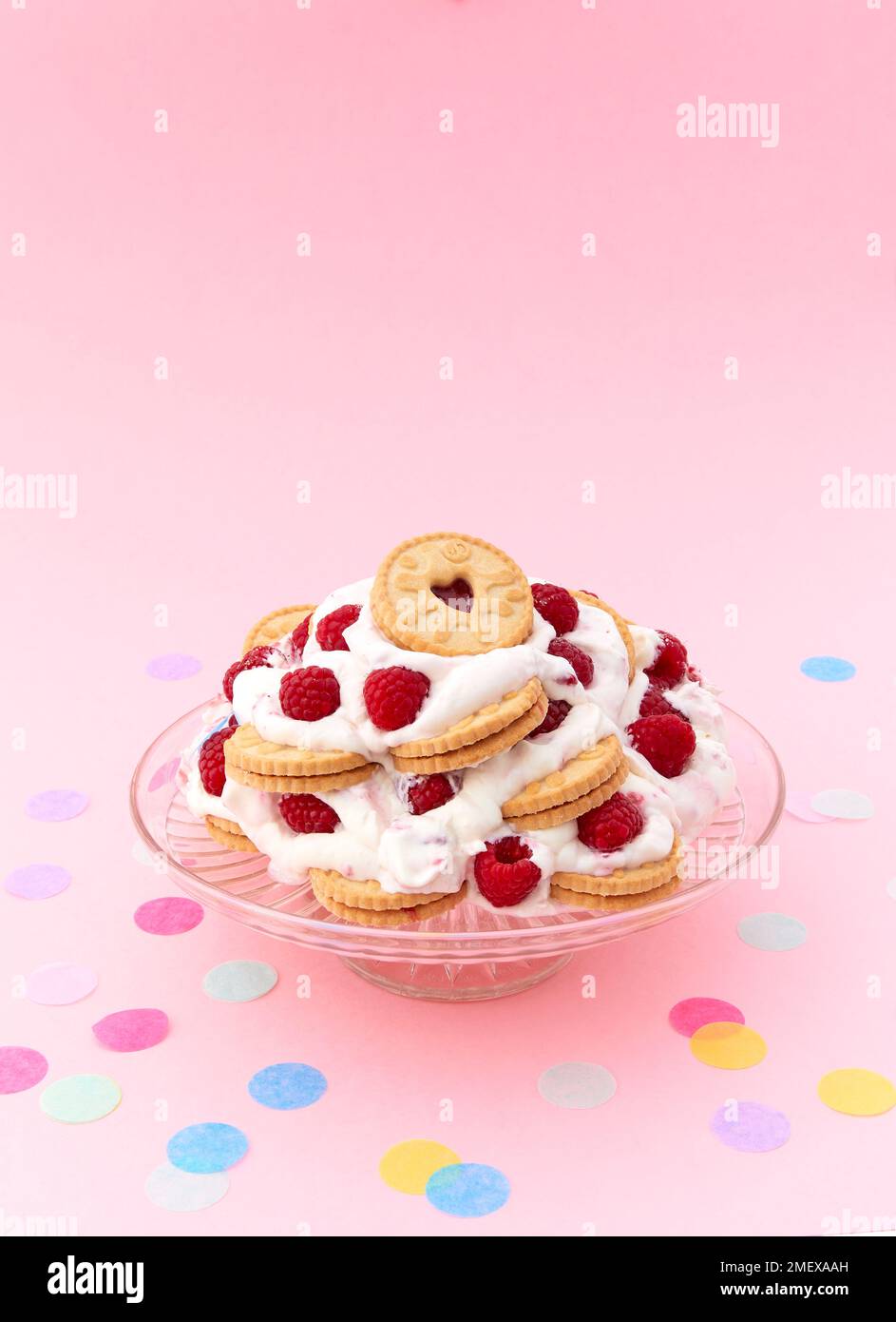 Himbeertorte mit Wellenschliff, Seite am Kuchenständer mit Konfetti Stockfoto