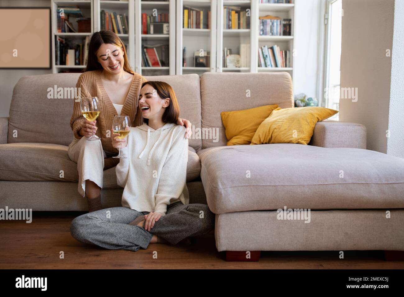 Fröhliche, lachende europäische Millenial-Freundinnen jubeln Gläser Wein, genießen Sie Ruhe, Entspannung und Zeit zur freien Verfügung zusammen Stockfoto