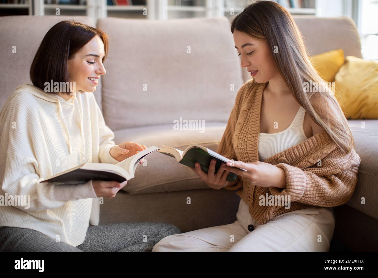Fröhliche, hübsche damen der Millennials in Pullover lesen Bücher, reden, genießen Ruhe, entspannen und Freizeit Stockfoto